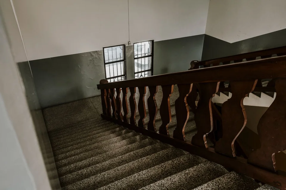 Cage d’escalier d’immeuble ancien, rampe en bois et murs peints en deux tons