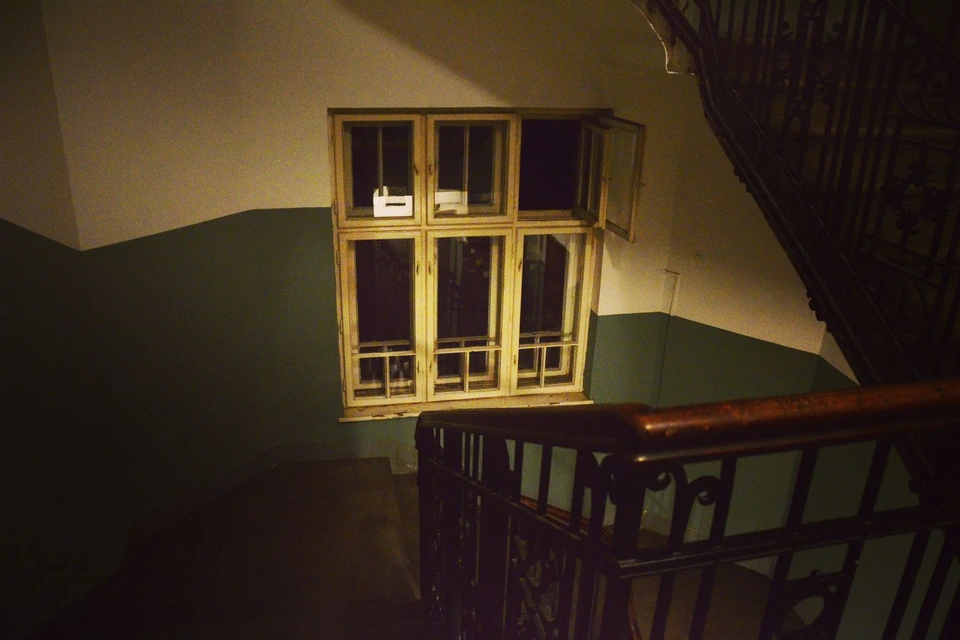 Palier d’immeuble ancien avec fenêtre et rampe en fer forgé