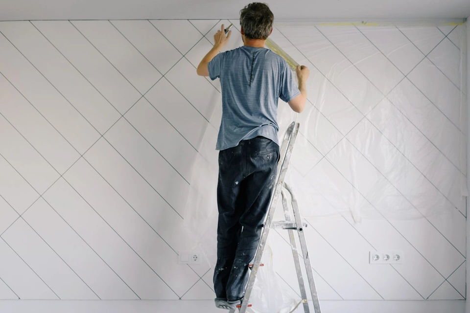 Peintre sur un escabeau en train de préparer un mur blanc