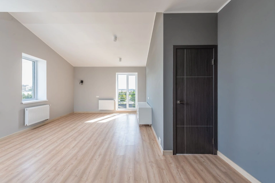 Pièce vide aux murs gris et au parquet clair