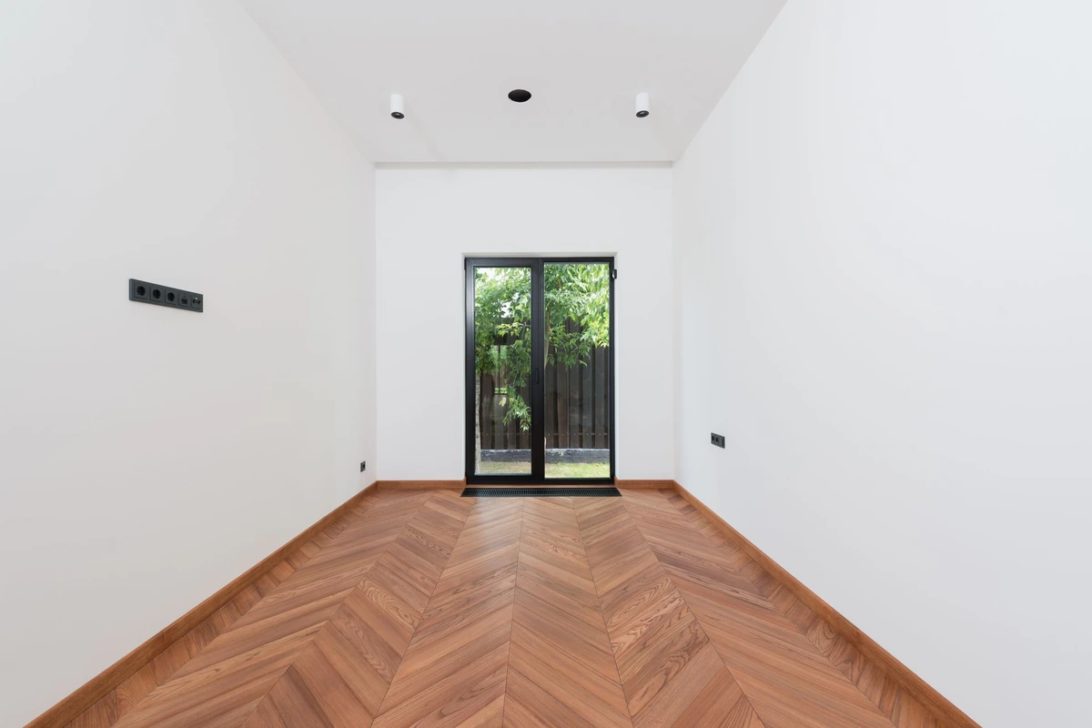 Pièce vide aux murs blancs avec un parquet posé en chevrons